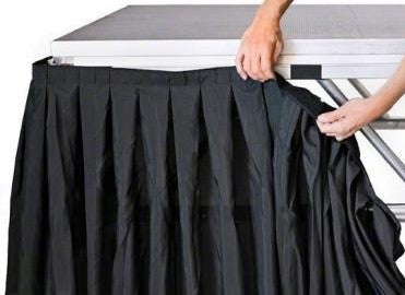 ruffled, black stage skirting being connected to a stage platform with velcro