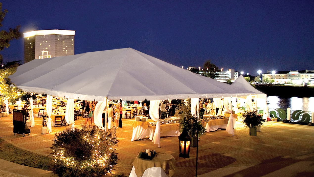 a formal wedding taking place in the evening under a well-lit West Coast Frame Tent